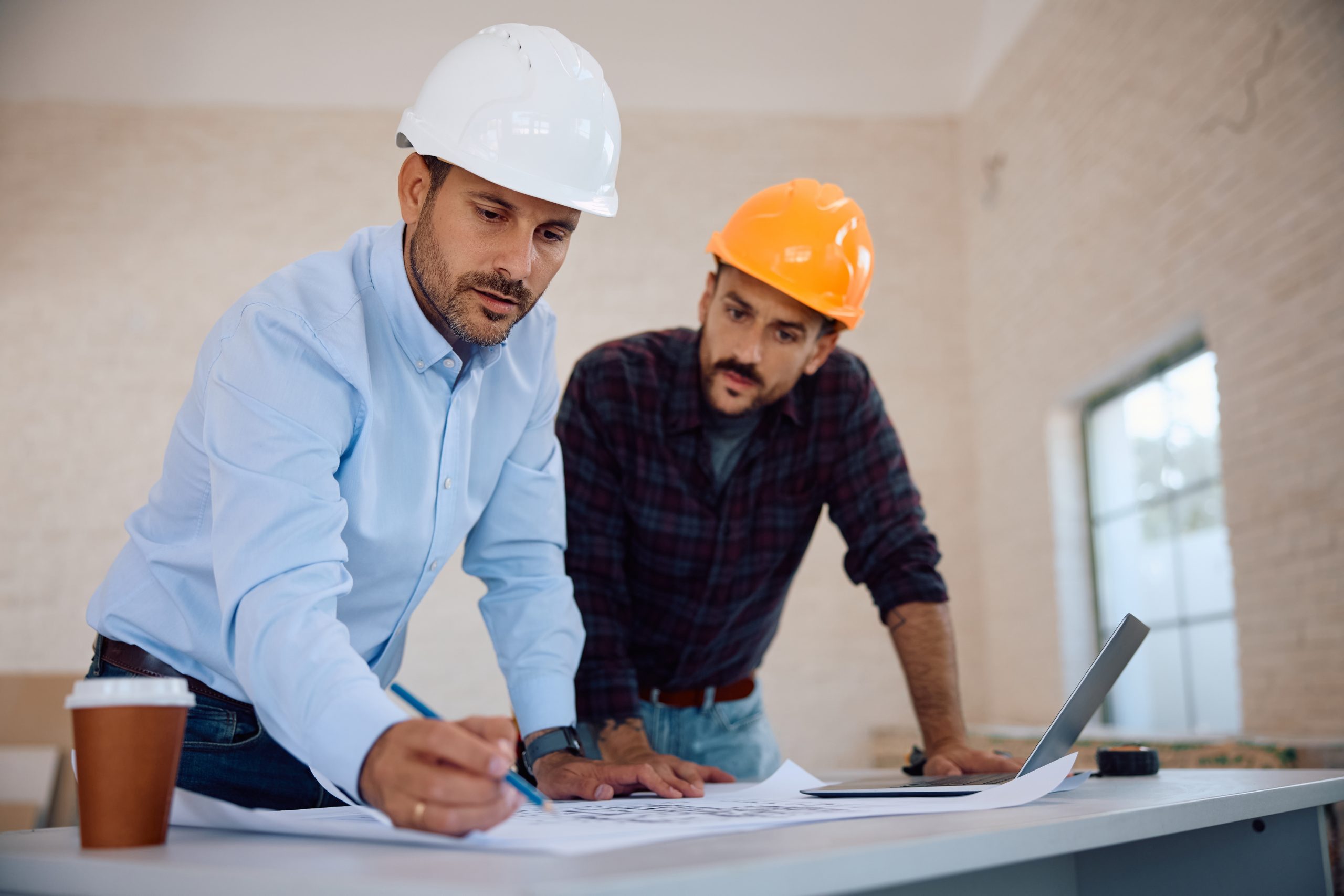 Mid,Adult,Architect,Analyzing,Housing,Plans,With,A,Worker,At